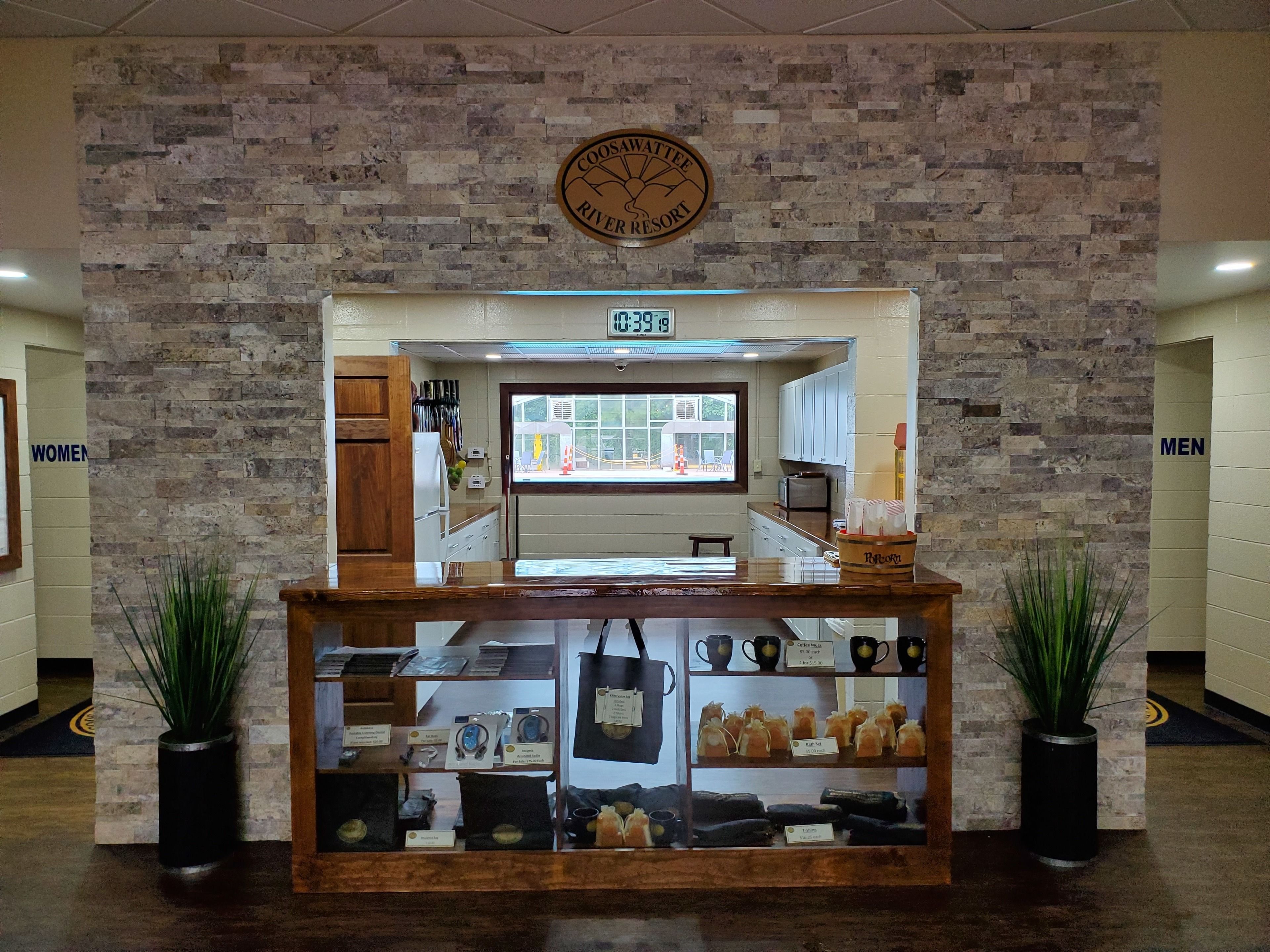 A coffee shop counter with a menu board, a clock, and a sign for Coosahatchee River Resort.