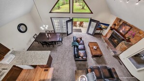 A spacious living area with a fireplace, a dining area, and a view through large windows.