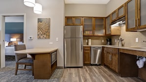 Una cocina moderna con armarios de madera, un refrigerador de acero inoxidable y un comedor con mesa y silla.