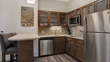 A modern kitchen with wooden cabinets, a stainless steel refrigerator, a built-in microwave, and a dishwasher.