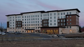 Un hotel Staybridge Suites con varios pisos, un estacionamiento y una entrada bien iluminada.