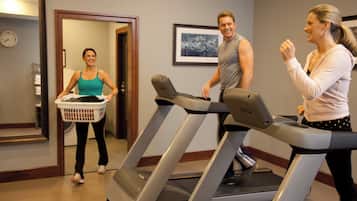 A fitness room with treadmills, a wall clock, and a door leading to another room.