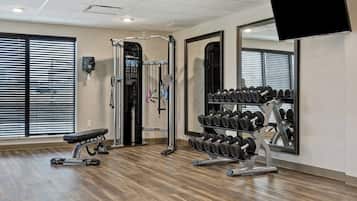 A gym with exercise equipment, a bench, and a mirror.