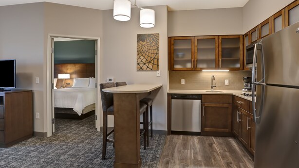 Una cocina moderna con armarios de madera, un refrigerador de acero inoxidable y un comedor con mesa y sillas.