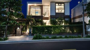 A modern two-story building with a well-lit entrance, a covered outdoor area, and a landscaped garden. - Wyndham Grand KN Paradise Cam Ranh (Bac Cam Ranh)