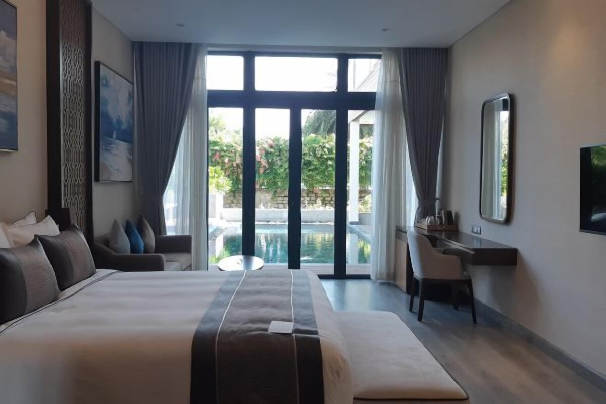 Une chambre d’hôtel moderne avec un grand lit, un bureau et une vue sur une piscine.