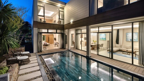 A modern house with a swimming pool, large windows, and a well-lit interior. - Wyndham Grand KN Paradise Cam Ranh (Bac Cam Ranh)