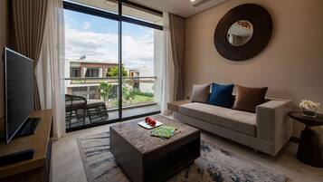Una sala de estar moderna con un ventanal grande, un sofá, una mesa de centro y un televisor.