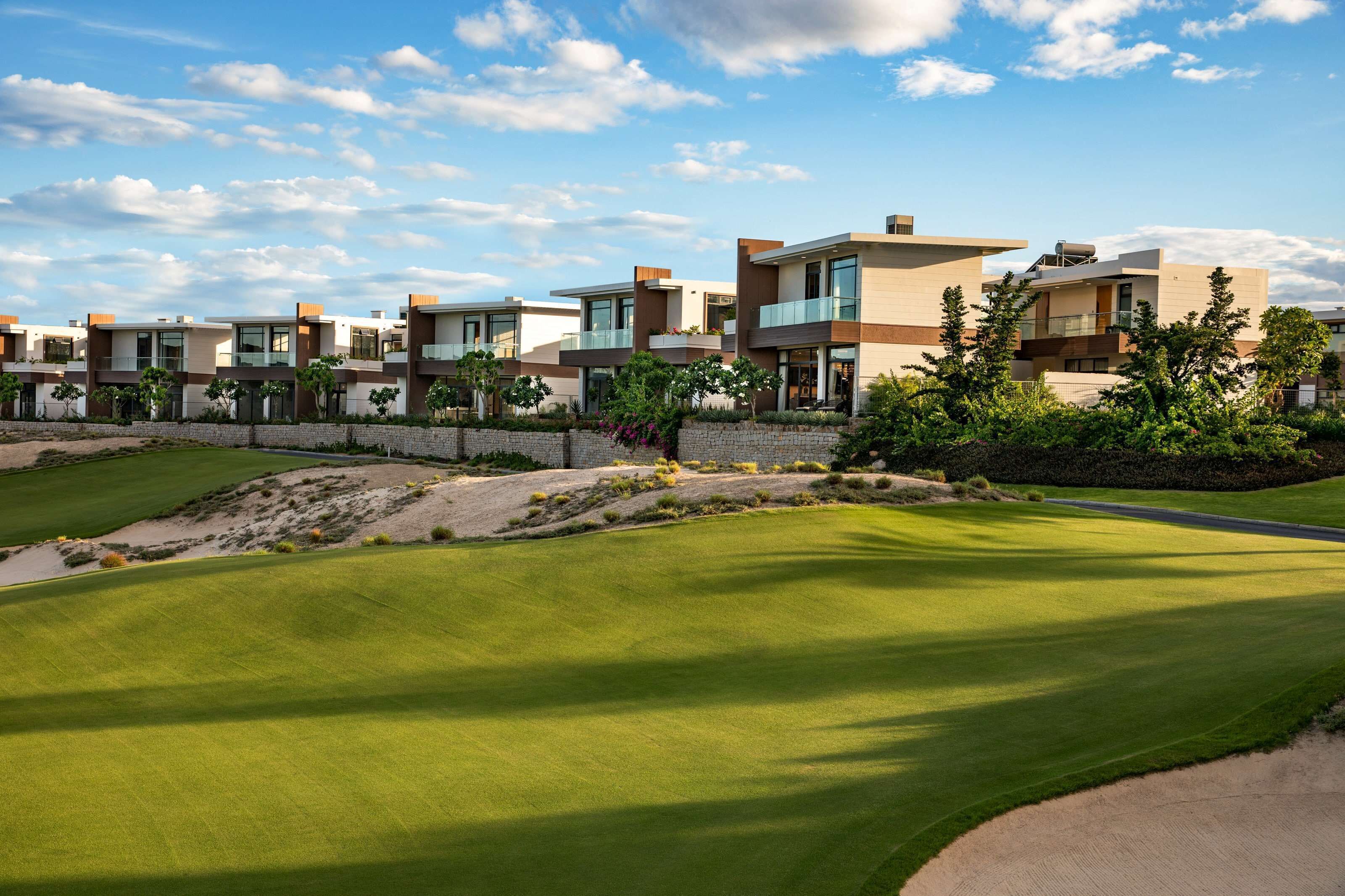 A modern residential area with contemporary houses, a well-maintained golf course, and a clear sky.