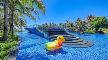 A swimming pool with a duck float, palm trees, and a staircase leading to a higher level.