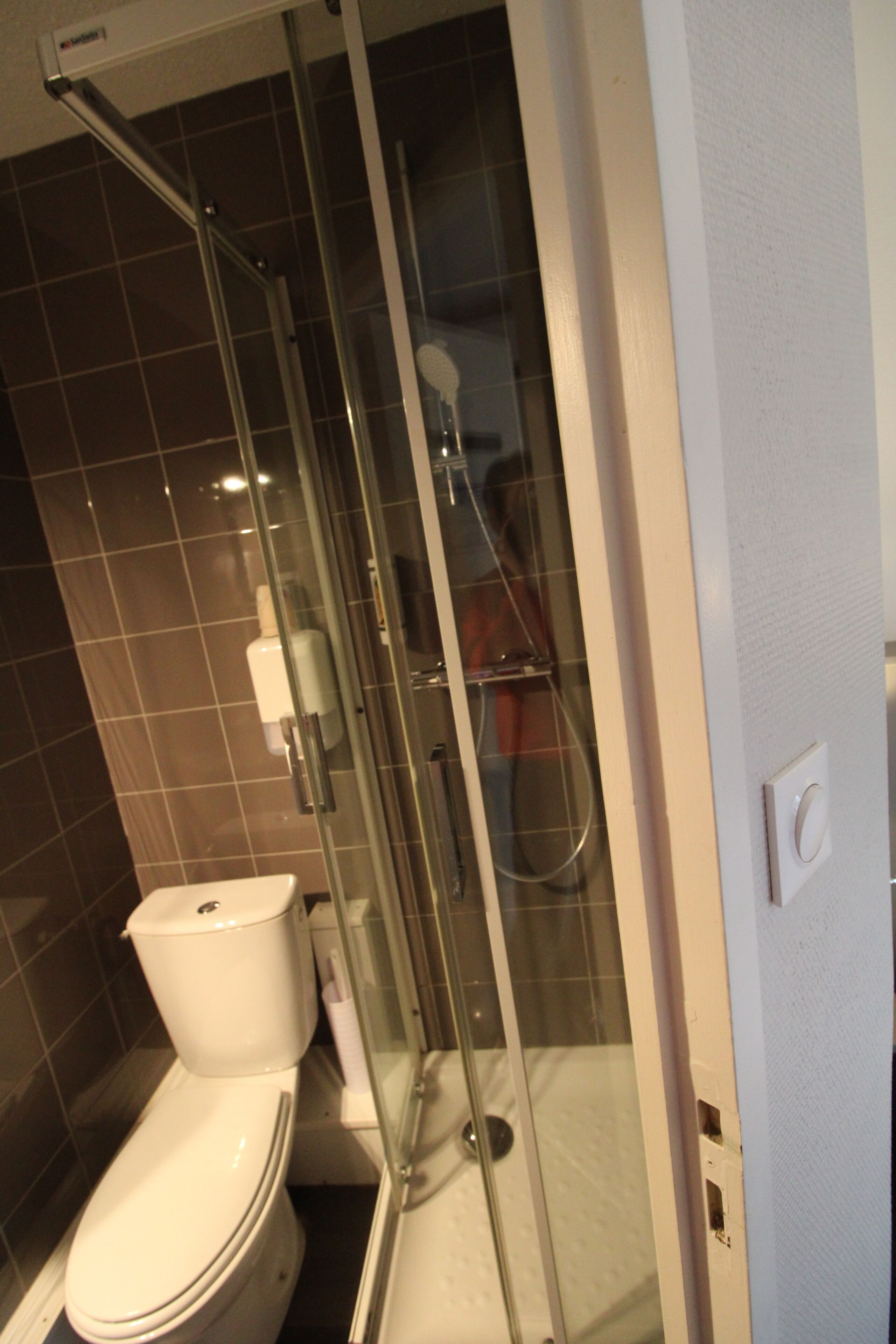 Une salle de bain avec une douche à parois de verre, des toilettes et un lavabo.