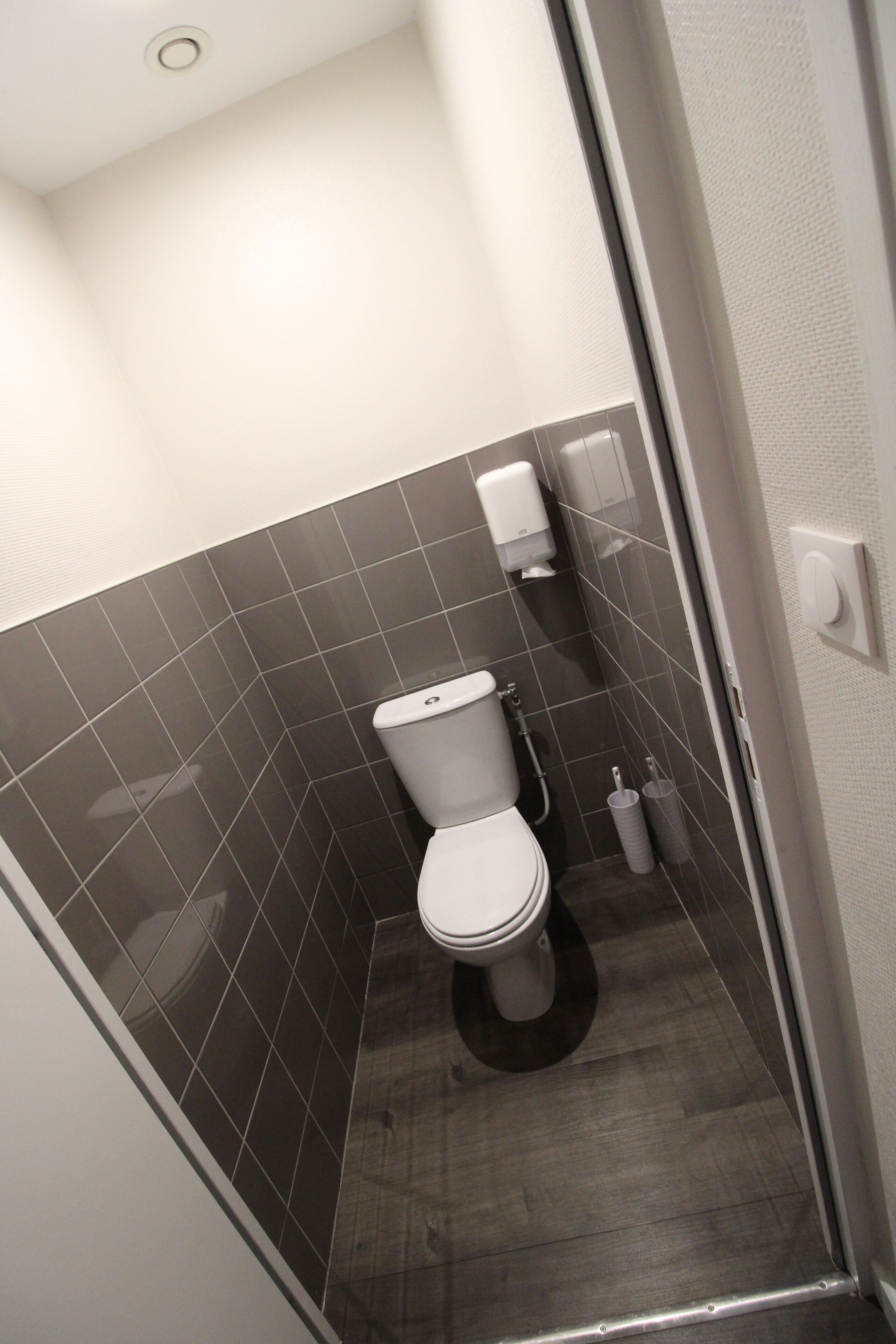 Ein modernes Badezimmer mit Toilette, einem Händetrockner und einem Mülleimer.