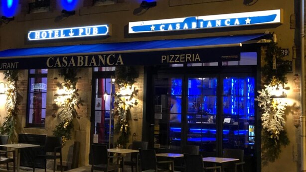Un bâtiment sur lequel on peut lire les inscriptions « CASABIANCA PIZZERIA » et « HÔTEL-BAR ».
