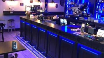 A bar area with a counter, stools, and a neon blue light strip.