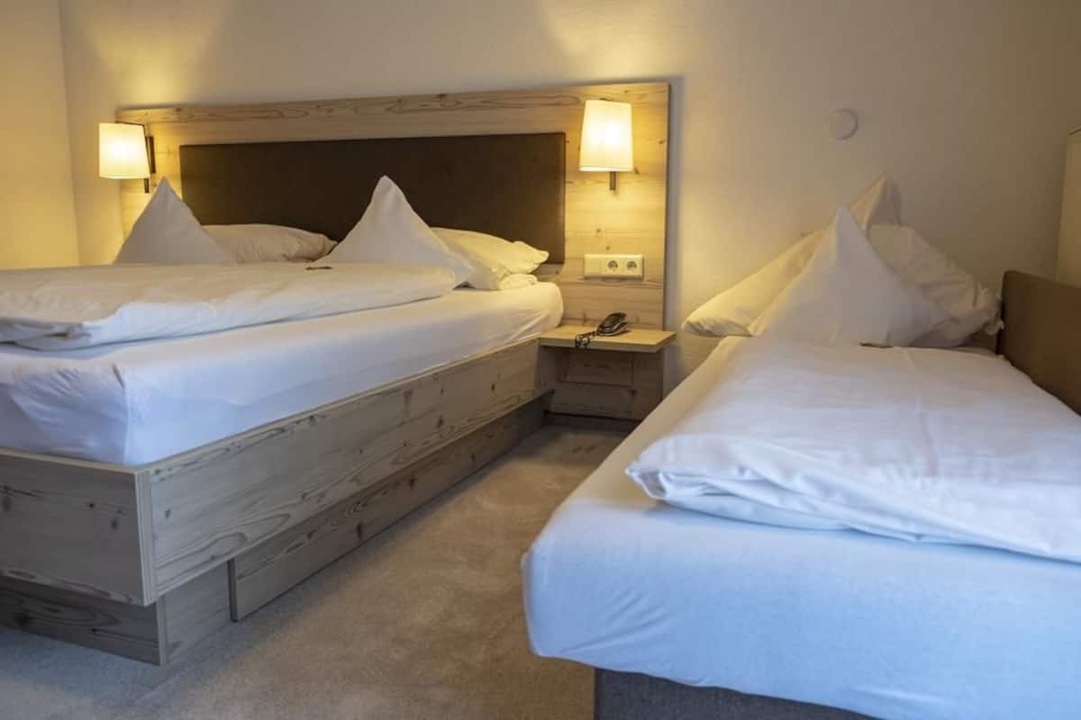 Une chambre d’hôtel avec deux lits, chacun doté de draps et d’oreillers blancs, de têtes de lit en bois et de lampes de chevet.