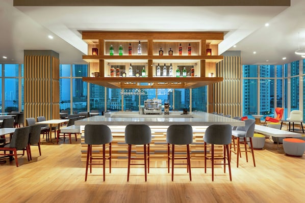 Un bar moderno con diversas opciones de asientos y vista panorámica de la ciudad.
