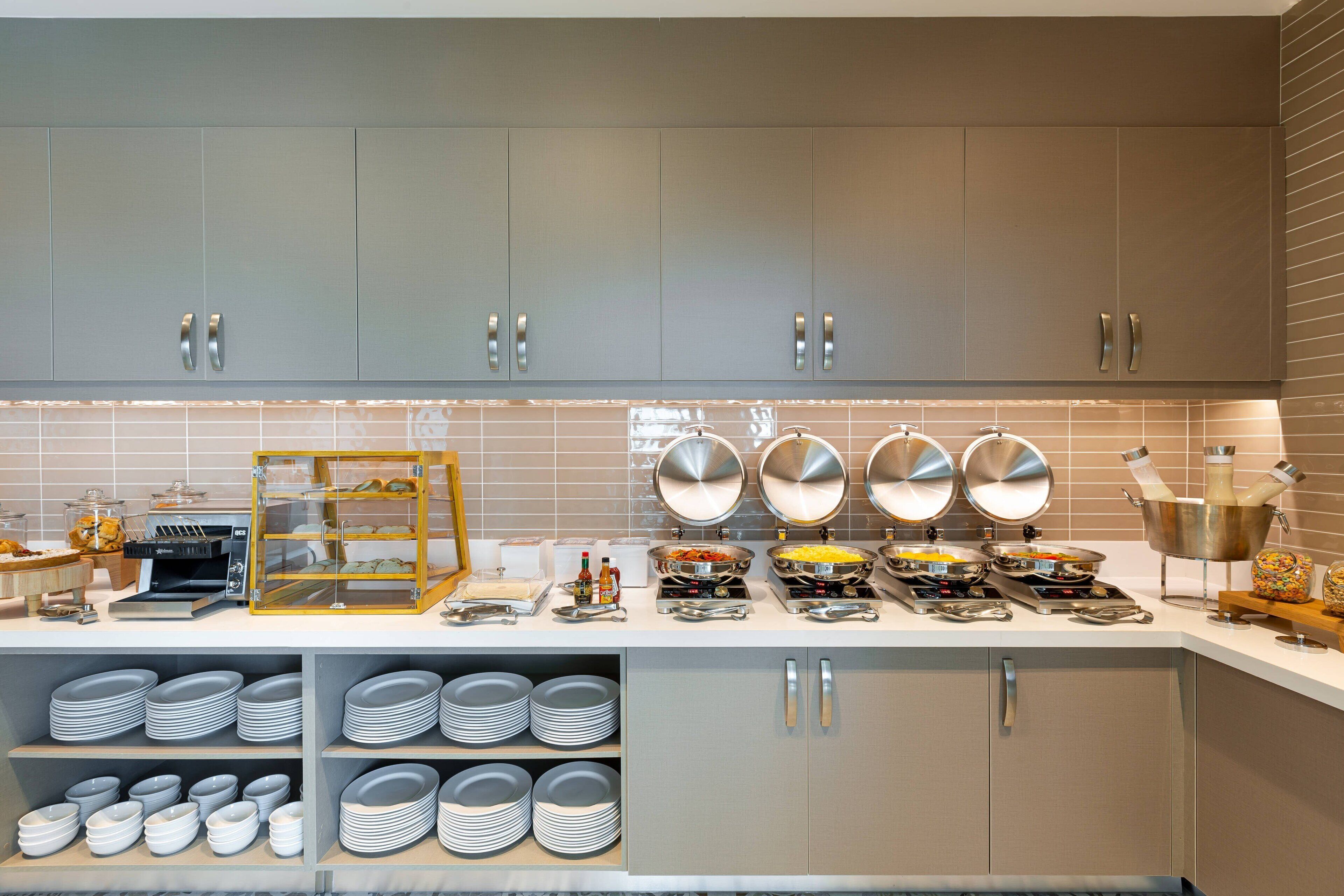Una cocina moderna con gabinetes grises, un espacio para café y platos apilados ordenadamente.