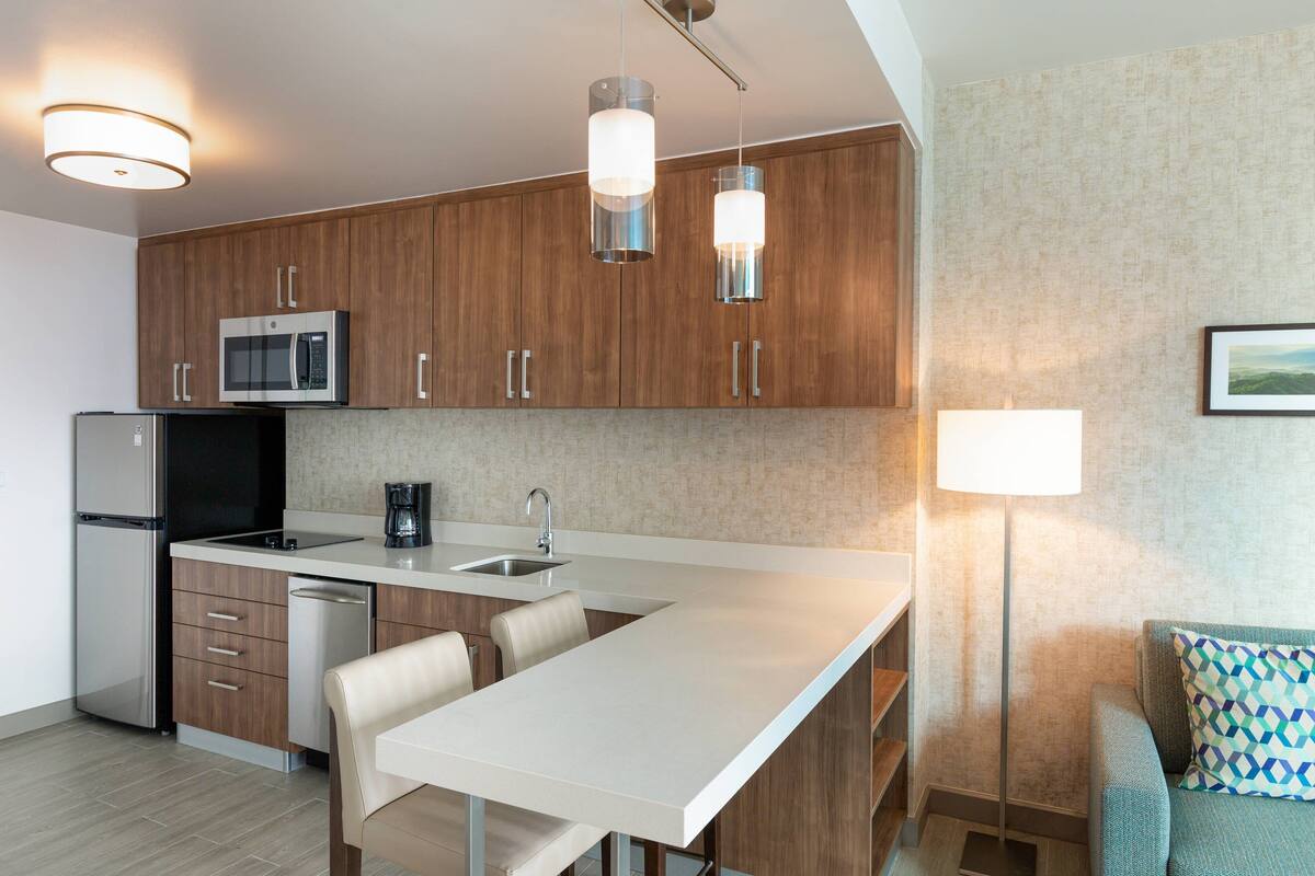 A modern kitchen with wooden cabinets, stainless steel appliances, and a white countertop.