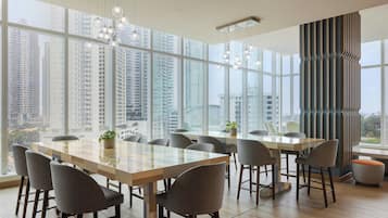 Un salón de conferencias moderno con ventanas amplias, una larga mesa y varias sillas.