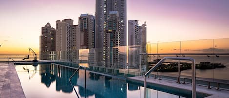 Una piscina al aire libre, sombrillas, sillones reclinables de piscina