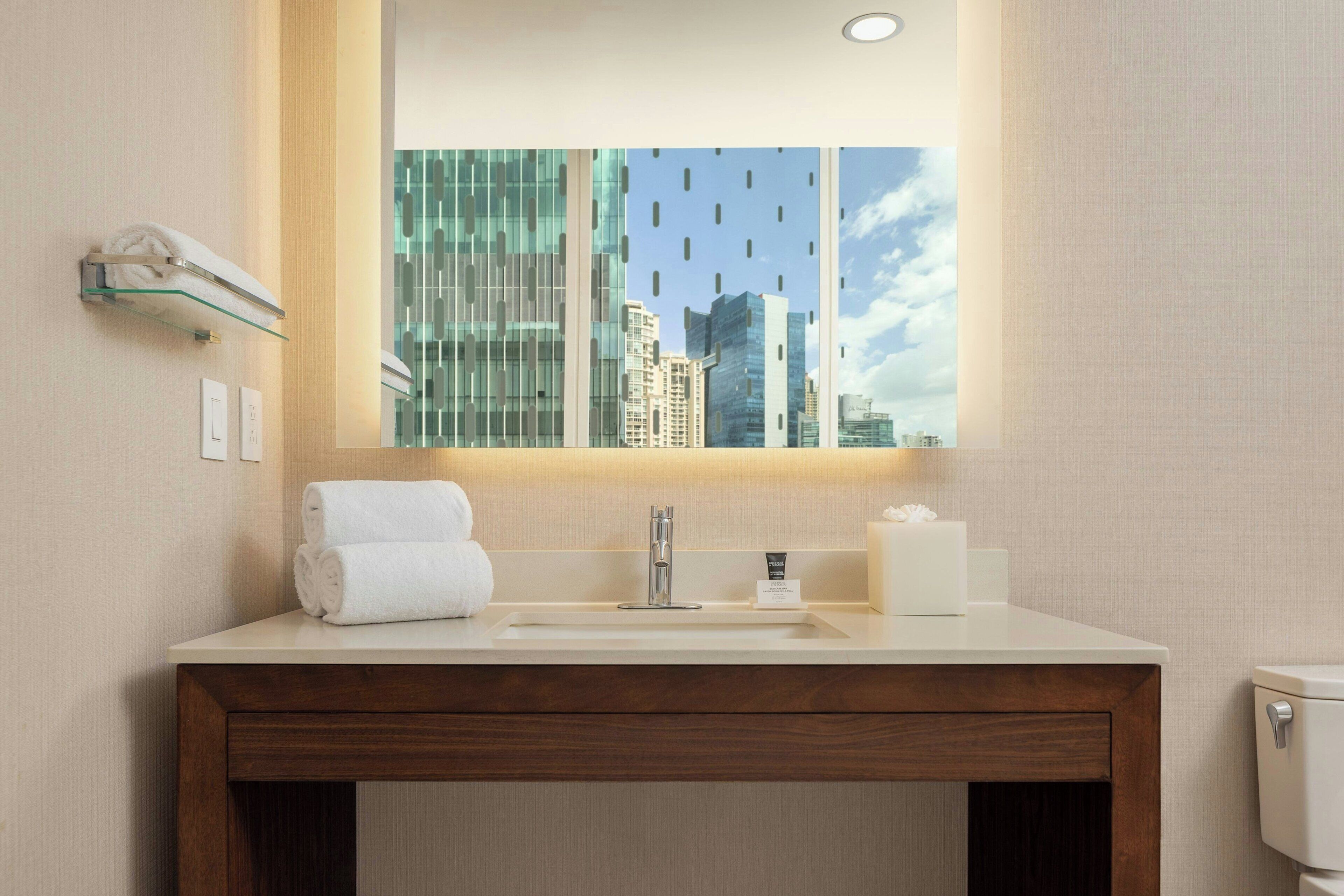 A modern bathroom with a large mirror, a sink, and a toilet.