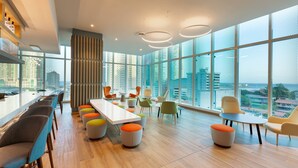 Une salle de conférence moderne, dotée d’une longue table, de chaises colorées et de grandes fenêtres offrant une vue sur la ville.