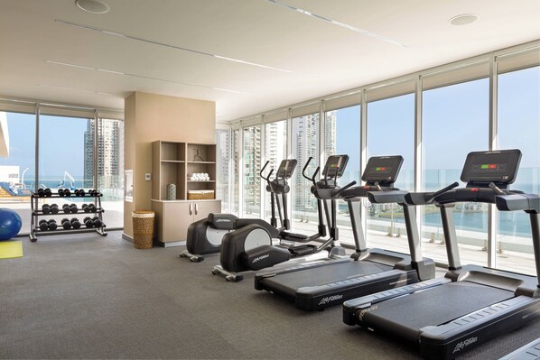 Un gimnasio con cintas de correr, elípticas y mancuernas.