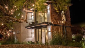 A modern house with a stone foundation, large windows, and outdoor lighting.