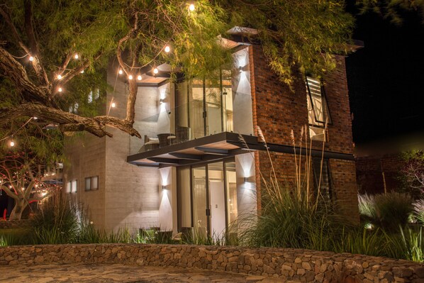 Una casa moderna con base de piedra, ventanas amplias e iluminación exterior.