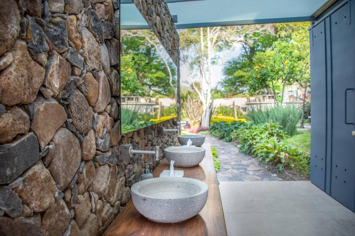 A stone wall with a wooden countertop and three large stone sinks.