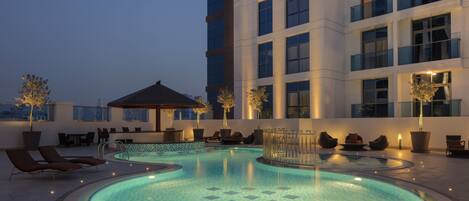 Alberca al aire libre, sombrillas en la alberca y camastros