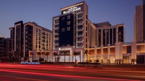 Um hotel de vários andares com uma placa chamativa 'Hyatt Place', apresentando um design arquitetônico moderno com janelas amplas e fachada bem iluminada.