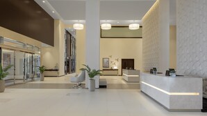 Um hall de hotel moderno, com balcão de recepção, área de estar e grandes colunas.