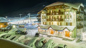 A multi-story hotel with a snow-covered roof and illuminated windows, situated in a snowy area with a ski lift in the background. - Hotel La Torretta (Vermiglio)