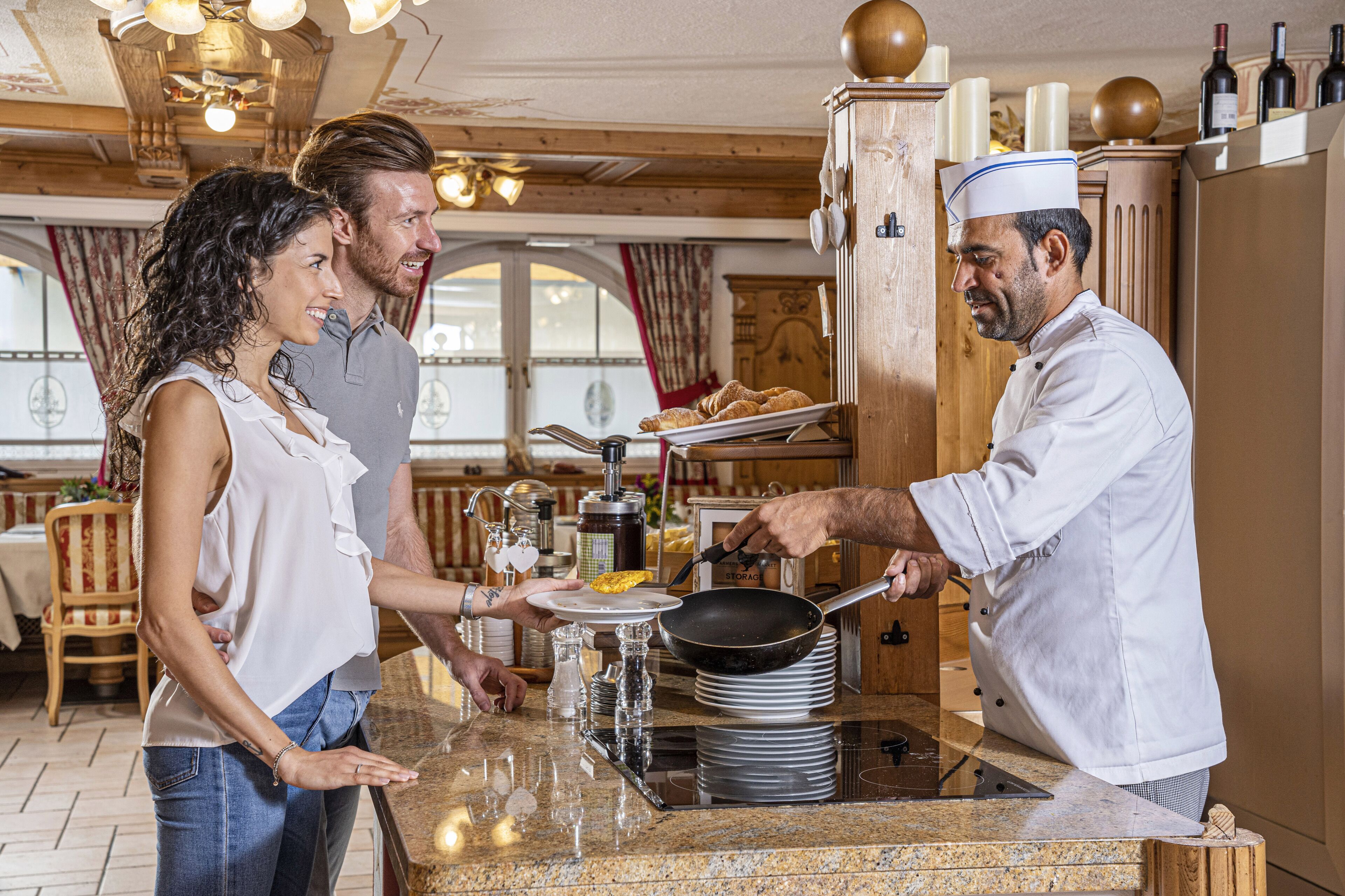 A chef serving food to guests in a restaurant with wooden decor and a traditional European style.