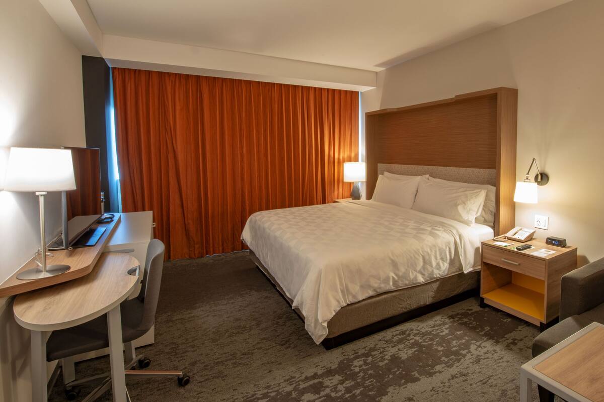 A hotel room with a bed, desk, chair, and a small sofa.