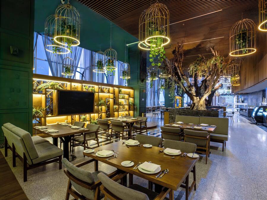 A modern restaurant with multiple dining tables, chairs, and hanging light fixtures.