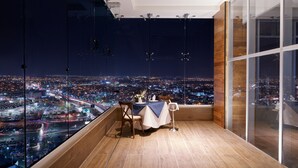 Quarto em um arranha-céu com vista panorâmica da cidade, mesa de jantar com cadeiras e design de interiores moderno.