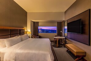 A hotel room with a large bed, a TV mounted on the wall, a small round table, and a bench. - Fiesta Americana San Luis Potosi (San Luis Potosi)