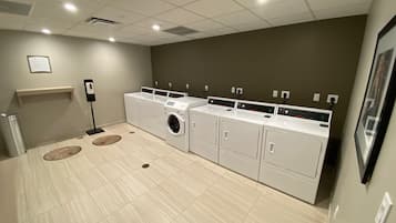 A laundry room with a washing machine, dryers, and a drying rack.