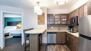 A compact kitchen with a dishwasher, microwave, and a dining area with a table and chairs.