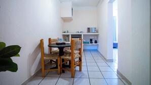 A compact kitchen with a dining area, white walls, and a ceiling fan. - Hotel Tropicus Boutique (Puerto Vallarta)