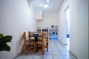 Une cuisine compacte avec un coin repas, des murs blancs et un ventilateur de plafond.
