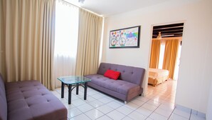 A living room with a sofa, a glass coffee table, and a framed picture on the wall. - Hotel Tropicus Boutique (Puerto Vallarta)