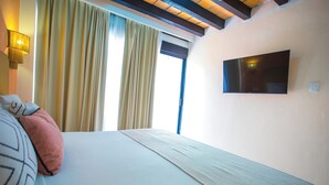 A hotel room with a bed, a TV mounted on the wall, and a window with curtains. - Hotel Tropicus Boutique (Puerto Vallarta)