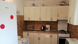 Una cuina compacta amb armaris blancs, forns a gas, microones i cafetera.