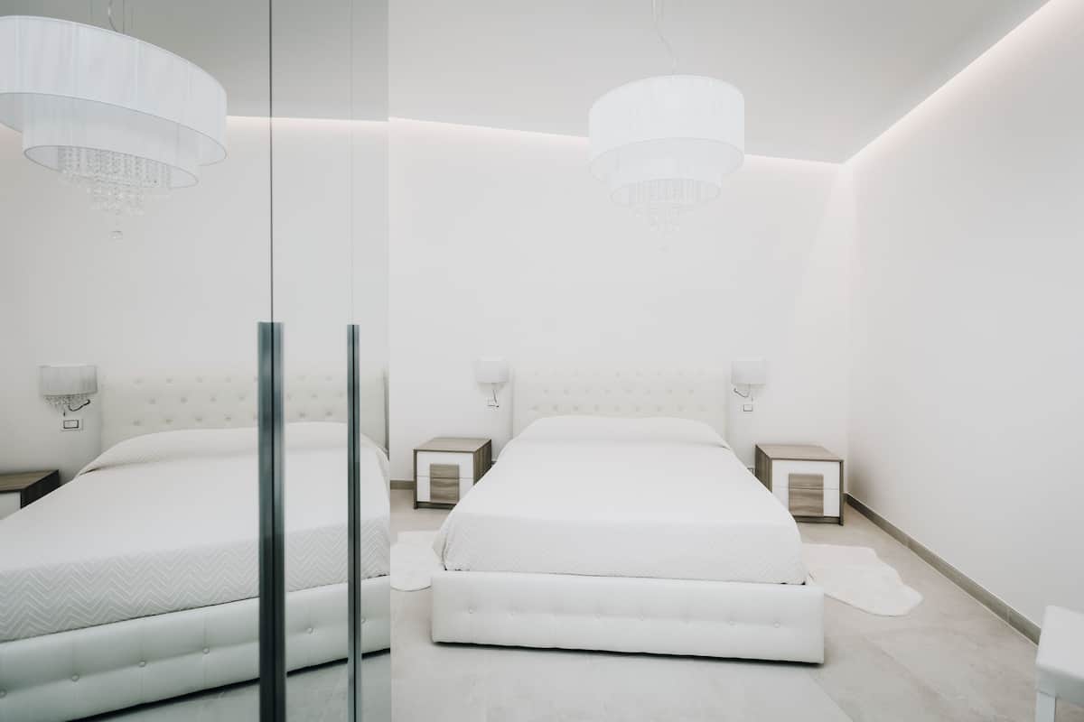 Une chambre à coucher moderne avec un grand lit, des tables de chevet et un lustre.