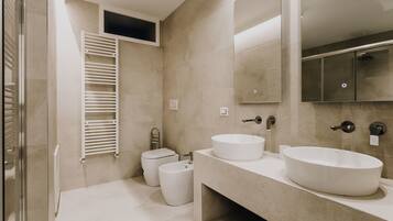 A modern bathroom with two sinks, a toilet, and a glass shower enclosure.