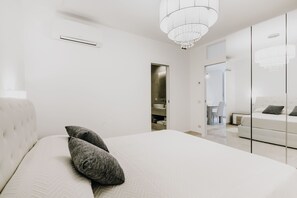 A modern bedroom with a large bed, a chandelier, and a walk-in closet. - Secret Garden - Suites & Apartments (Vasto)