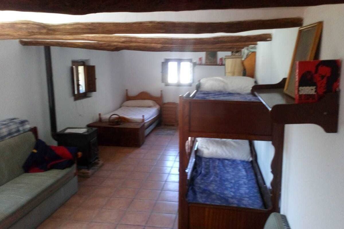 Une petite pièce agréable et chaleureuse, avec un lit superposé, un canapé et un plafond en bois.